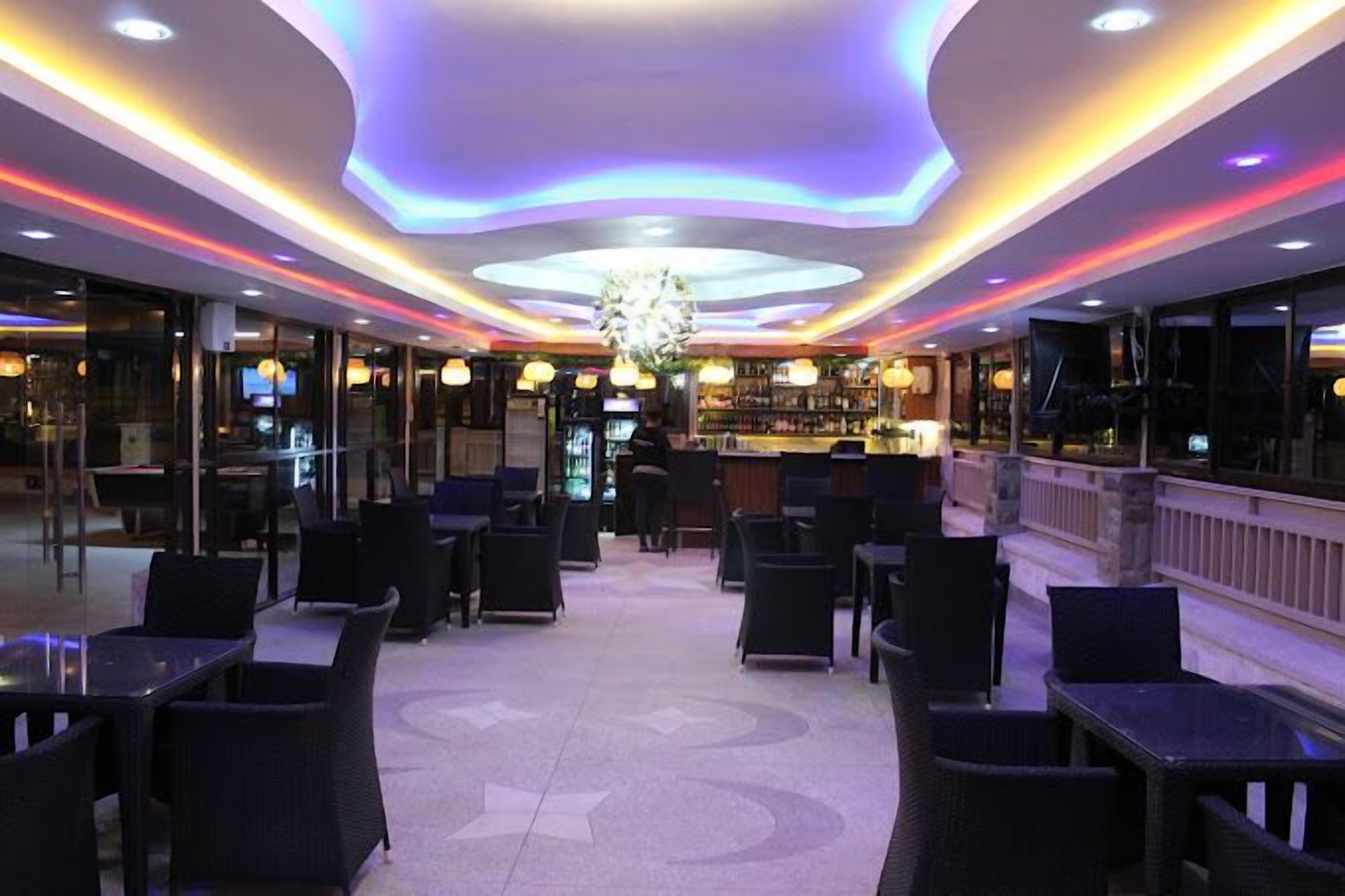 Vestíbulo de hotel con zona de bar central, rincones con asientos y techo decorativo.