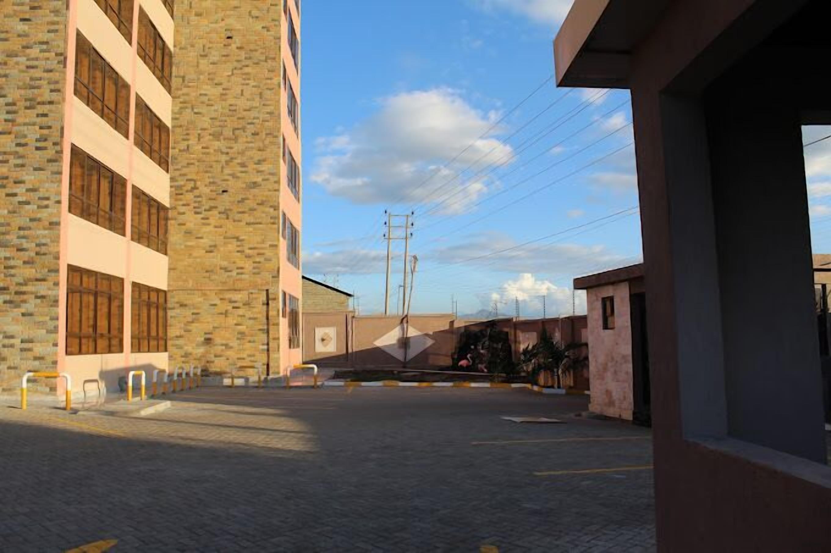 A building with a brick facade and large windows, a paved courtyard, and a clear sky.