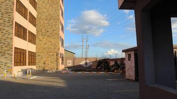 A building with a brick facade and large windows, a paved courtyard, and a clear sky.