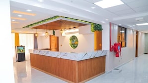 A reception area with a wooden reception desk, a digital screen, and a fire extinguisher on the wall. - Aqua Resort Naivasha (Naivasha)