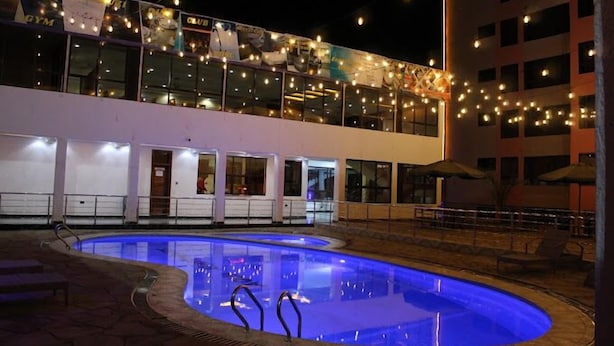 A pool area with a clear view of the pool, lounge chairs, and a building with multiple windows and balconies. - Aqua Resort Naivasha (Naivasha)