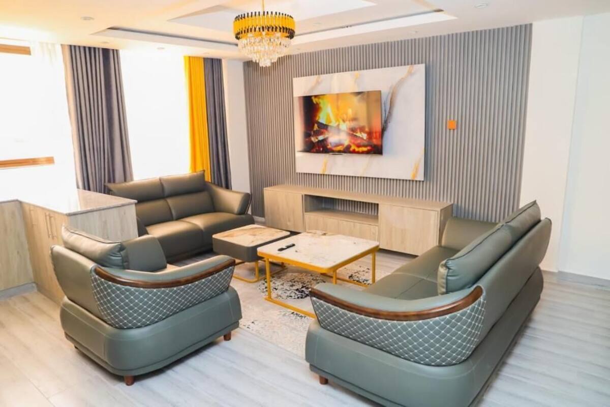 A modern living room with a sofa set, a coffee table, and a flat-screen TV mounted on the wall.
