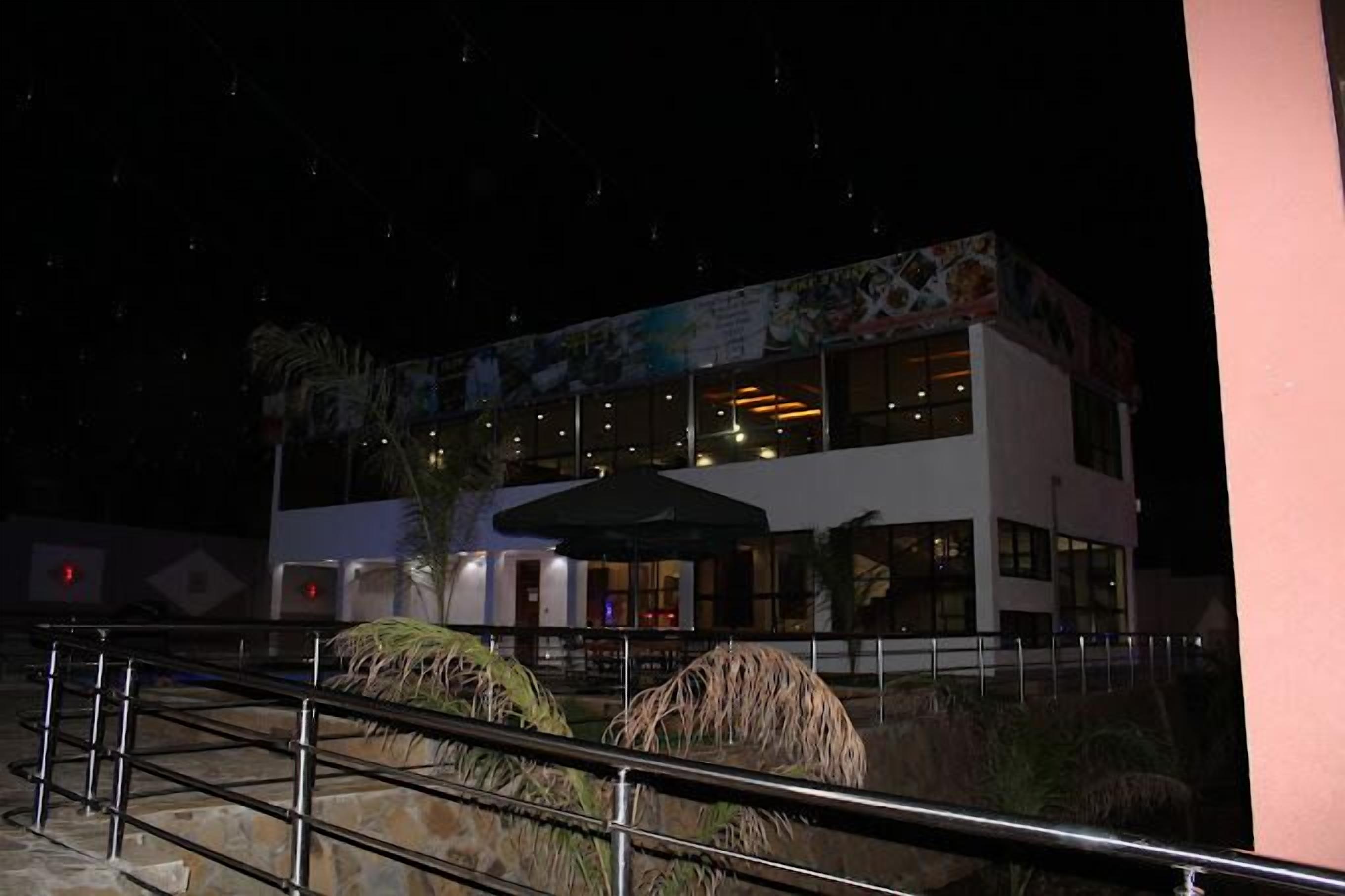 A two-story building with large windows and a covered outdoor seating area.