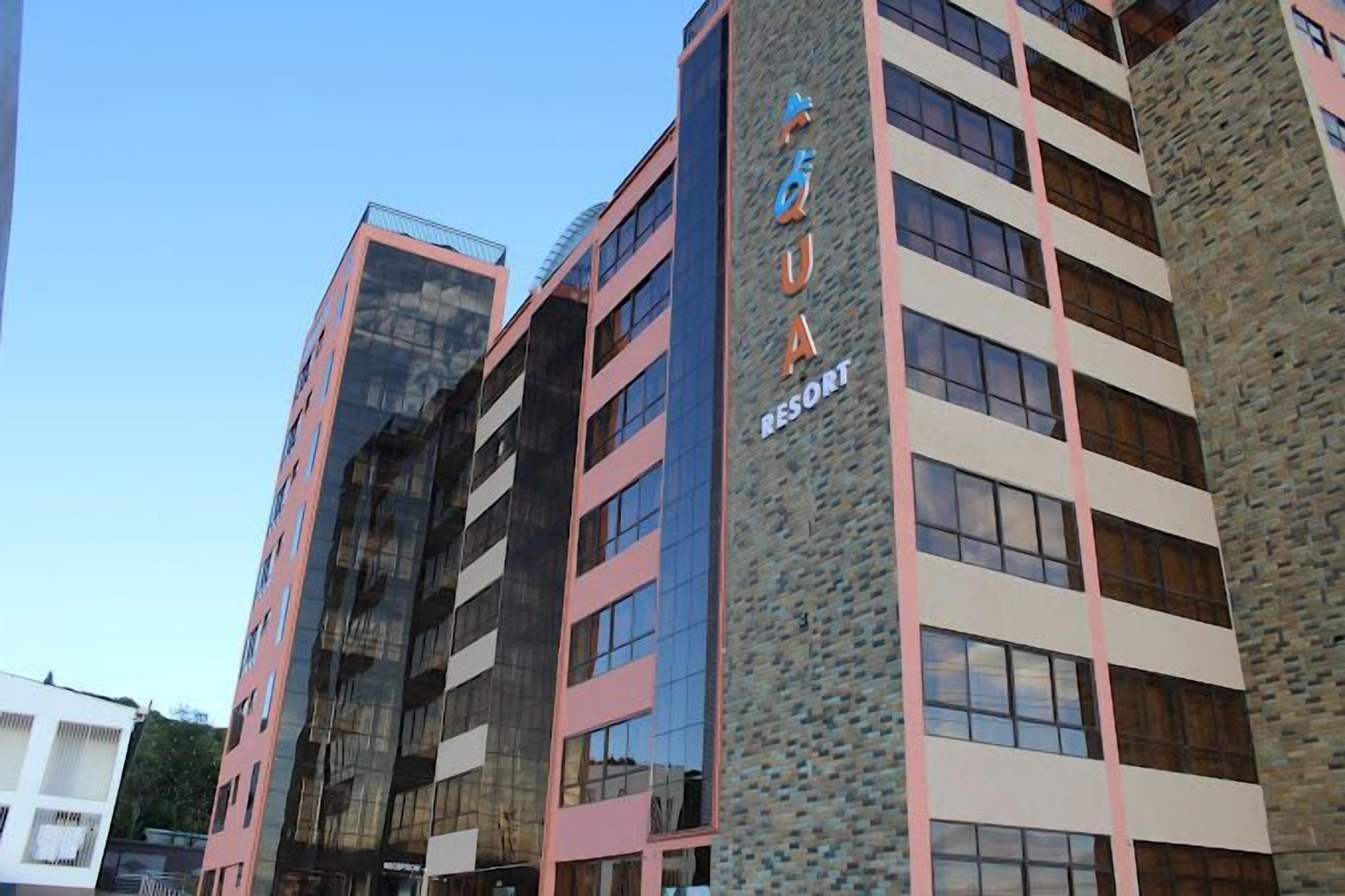 A multi-story hotel with a modern architectural design, featuring a prominent sign for "AQUA RESORT".