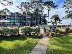 A multi-story residential building with balconies, a gated entrance, and a clear sky.