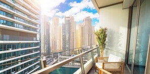 Un balcon avec vue sur des immeubles de grande hauteur, une piscine et une plante en pot.