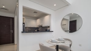 Una cucina moderna con una porta in legno scuro, uno specchio rotondo e un'area pranzo con tavolo apparecchiato per due.