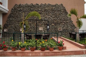 A stone wall with a garden in front, outdoor furniture, and a small fountain.