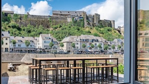 A terrace with a view of a historic town, stone walls, and a hill with buildings. - Vacation Home in Bouillon by Semois River (Bouillon)