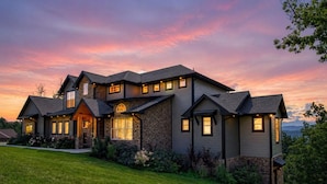 A two-story house with a stone facade, multiple windows, and a well-maintained lawn.