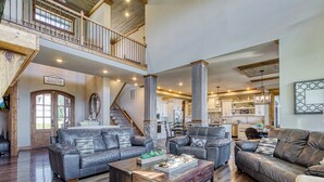 A spacious living room with leather sofas, a wooden coffee table, and a staircase leading to an upper level.