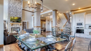 A spacious dining area with a glass table, surrounded by wooden chairs and a stone accent wall.