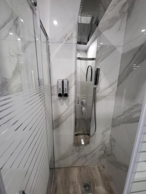 Une salle de bain moderne avec une douche en verre, des murs en marbre et un plancher en bois.