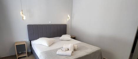 A modern bedroom with a large bed, a bedside table, and a hanging light fixture.