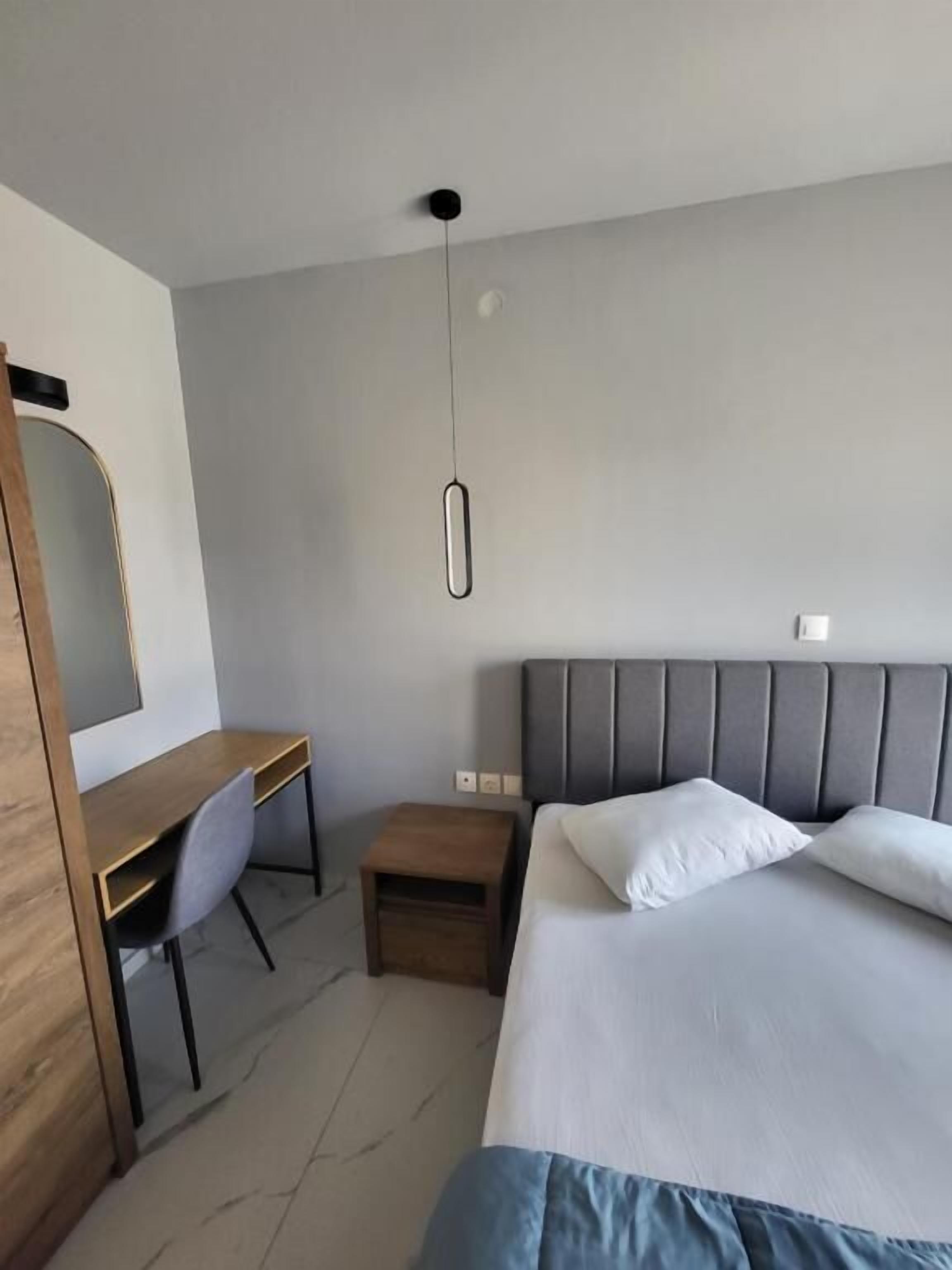 A modern hotel room with a bed, a desk, and a chair.