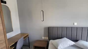 A modern hotel room with a bed, a desk, and a chair.