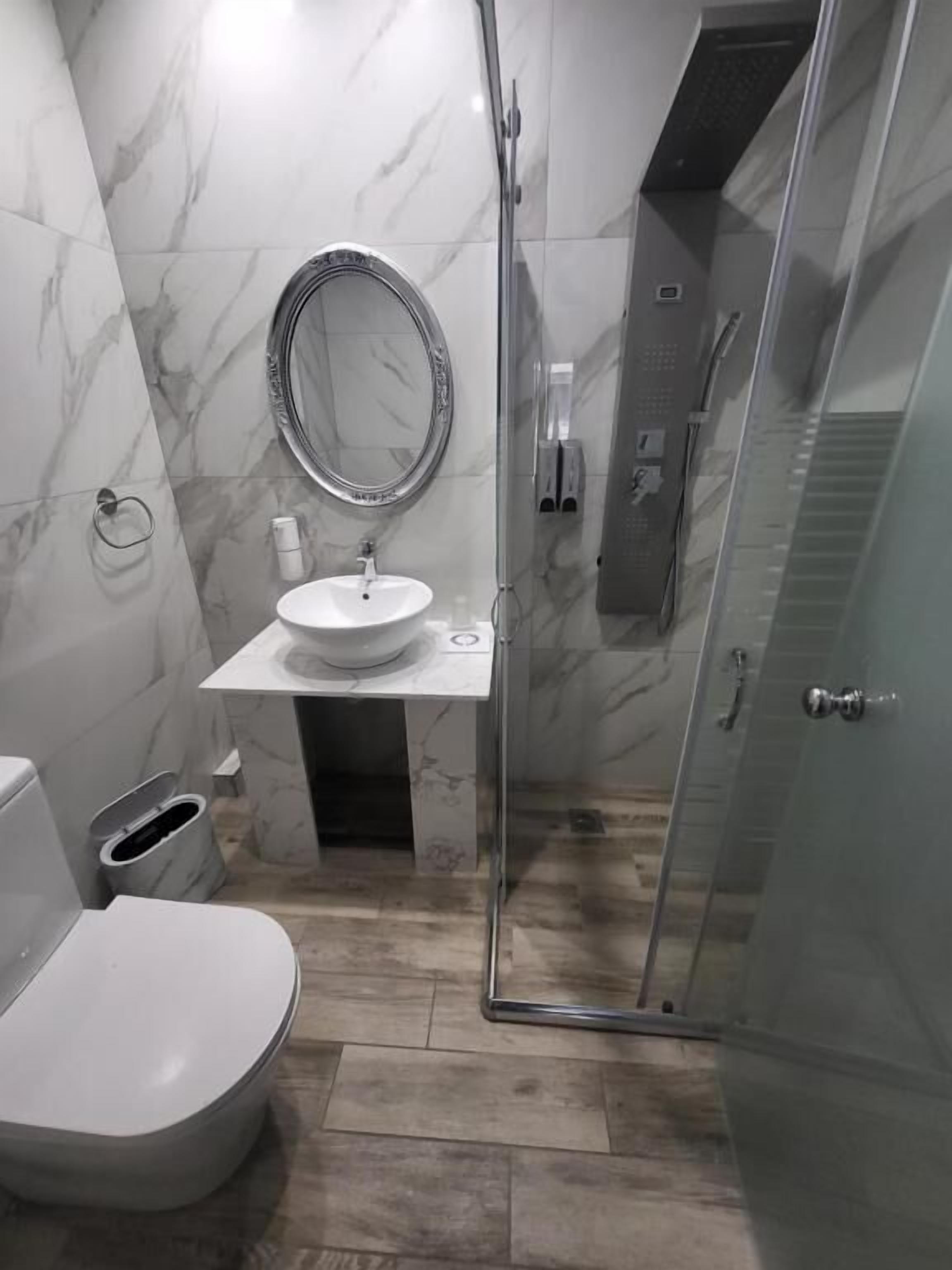 Un baño moderno con ducha de vidrio, un lavamanos blanco y un inodoro.