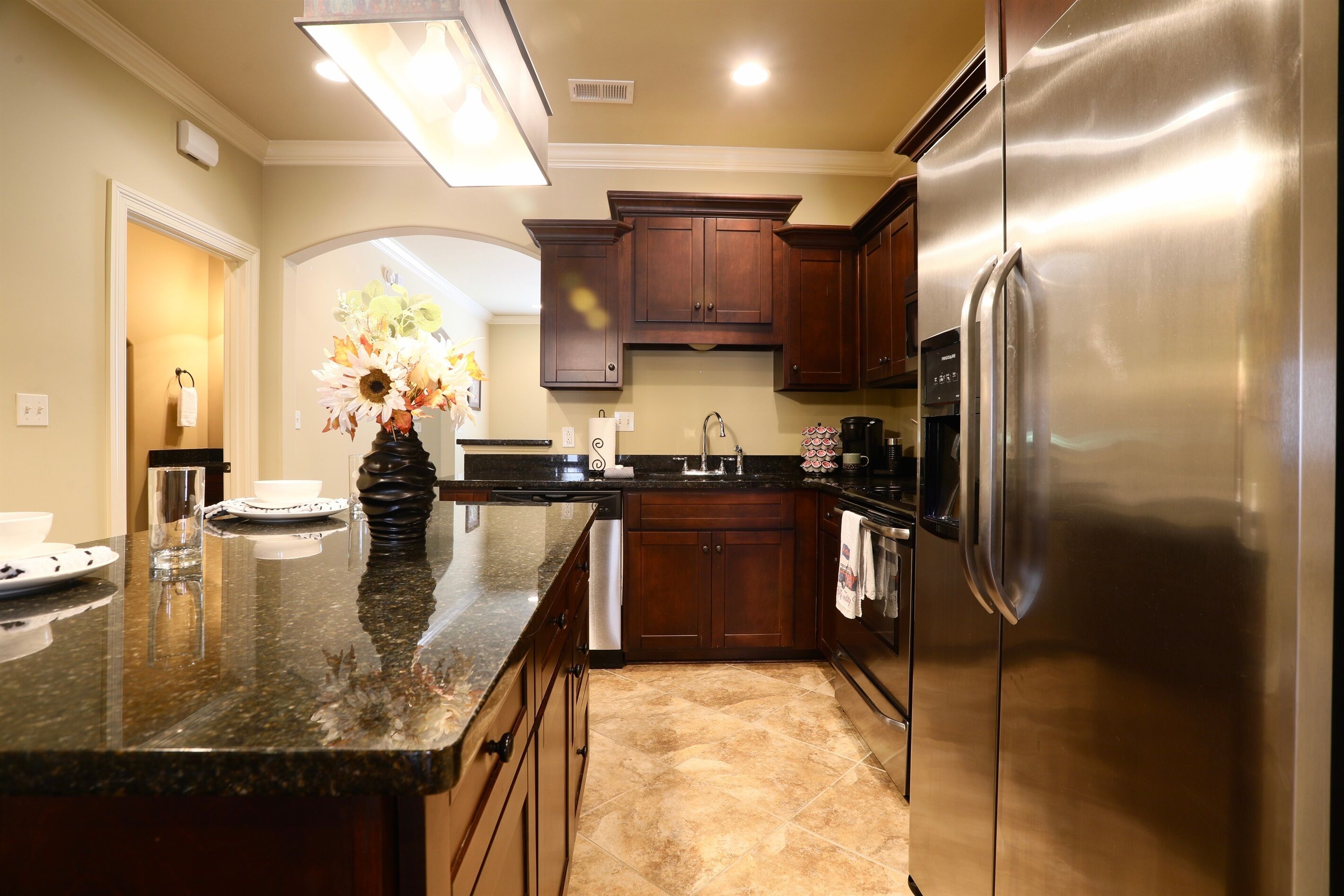 A modern kitchen with dark wooden cabinets, a stainless steel refrigerator, and a granite countertop.