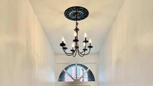 A hallway with a chandelier, a door with a window, and a view of a parked car outside. - Off Street Reserved Parking, Full Kitchen, Newly Renovated (Verona)