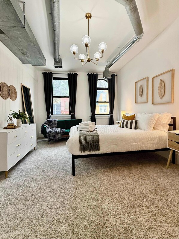 A bedroom with a bed, dresser, chair, and a ceiling fan.