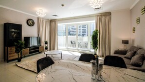 A modern living room with a marble coffee table, a flat-screen TV, a sofa, and a dining area with chairs. - Spacious 1BR with Balcony in JLT (Dubai)