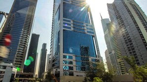 A high-rise building with a glass facade and multiple floors. - Spacious 1BR with Balcony in JLT (Dubai)