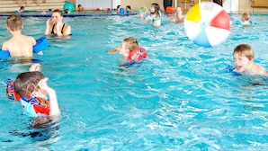 Ein Hallenbad mit mehreren Bahnen, einem Rettungsschwimmerstuhl und einem großen Strandball.
