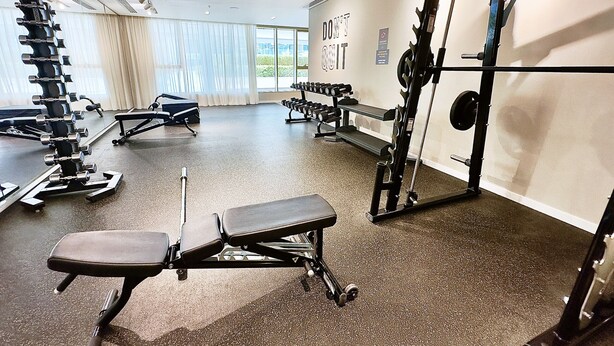 A gym with various exercise equipment, including dumbbells, benches, and a squat rack. - Modern 1BR Emaar Beachfront Near Marina JBR (Dubai)