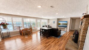A spacious living room with hardwood floors, a dining area, and a fireplace. - Lakefront 4BD/2.5BA Grill/Dock/Sleeps 13PP (Osage Beach)