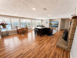A spacious living room with hardwood floors, a dining area, and a fireplace.