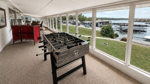 A foosball table in a room with large windows overlooking a marina. - Lakefront 4BD/2.5BA Grill/Dock/Sleeps 13PP (Osage Beach)