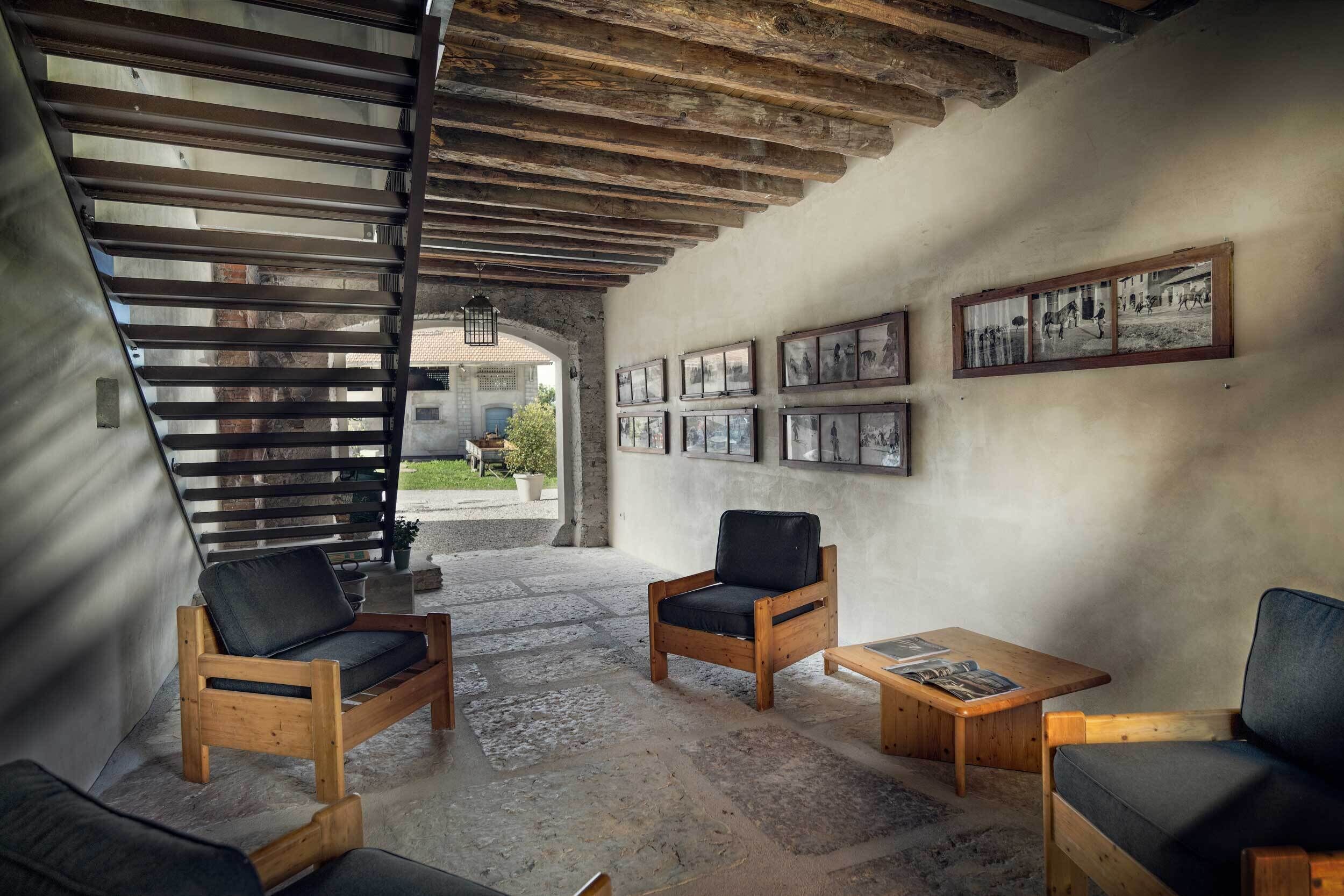 A rustic interior with wooden furniture, a stone floor, and framed pictures on the wall.