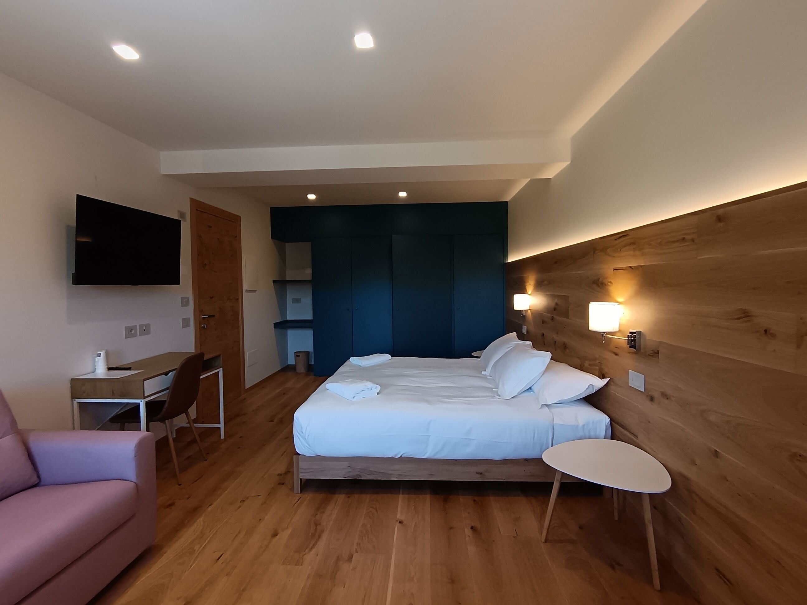 Una habitación de hotel moderna con una cama, una mesita de noche y un televisor montado en la pared.