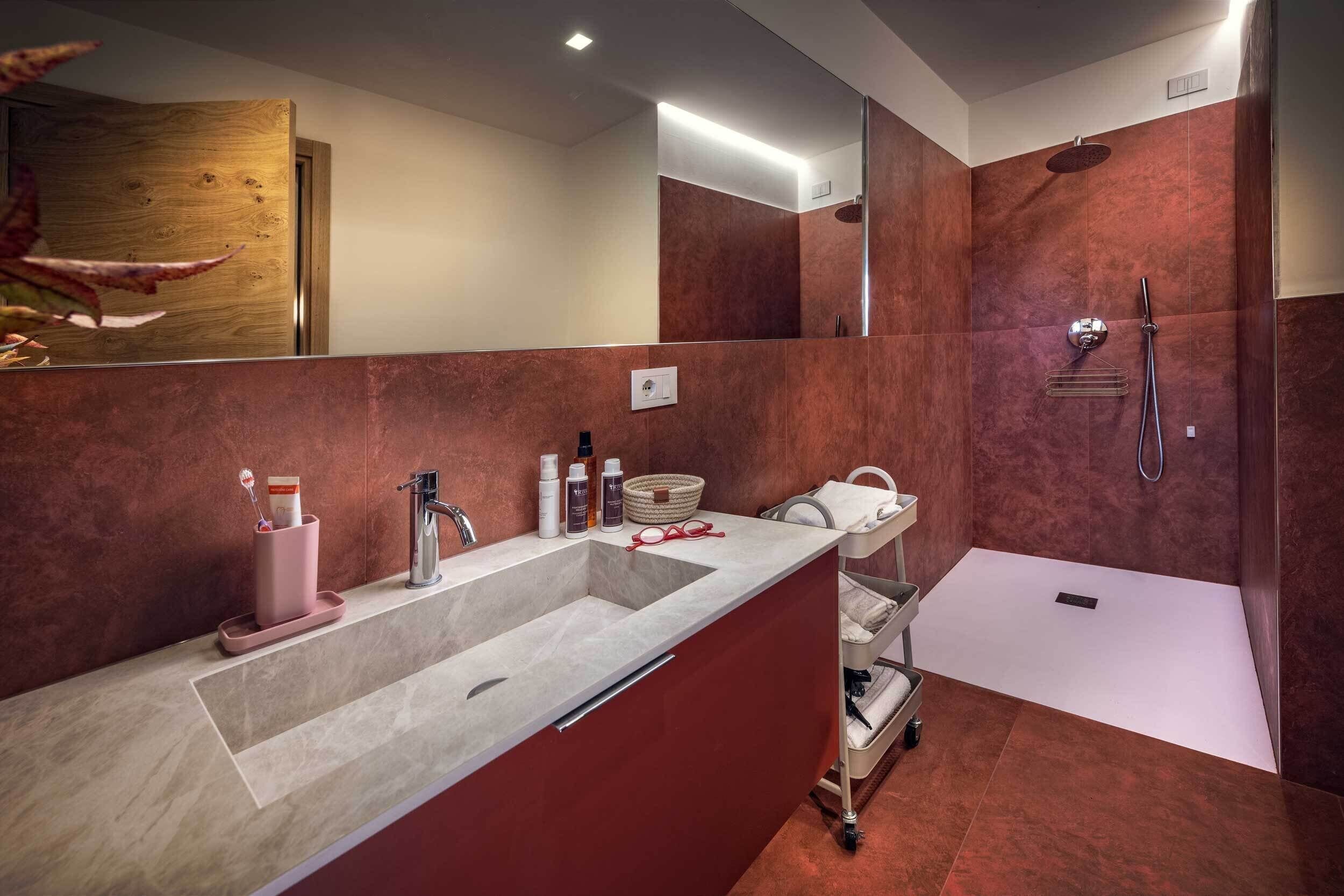 A modern bathroom with a large sink, a shower, and a vanity area.