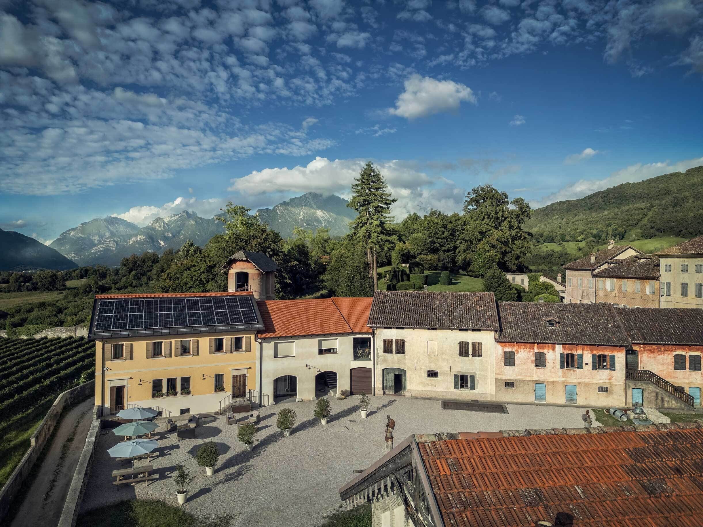 A building with a solar panel, a courtyard, and a mountainous backdrop.