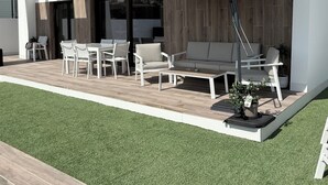 A modern outdoor patio with a pool, white furniture, and a pergola.