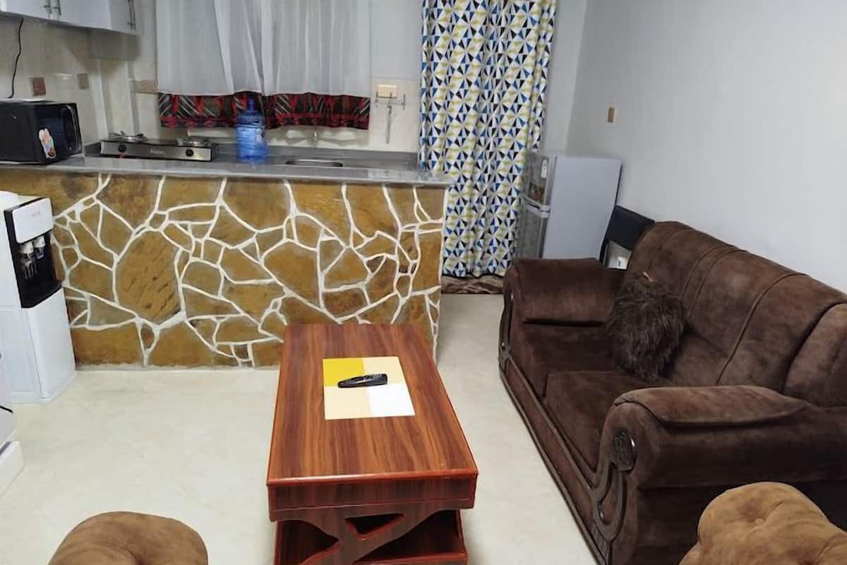 A living room with a brown sofa, a wooden coffee table, and a stone-patterned backsplash.