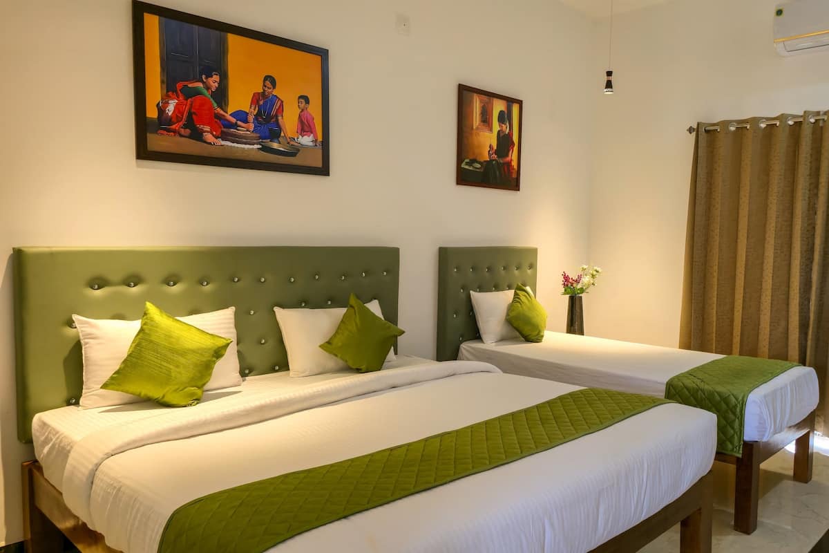 A hotel room with two beds, green headboards, white bedding, and a painting above the beds.