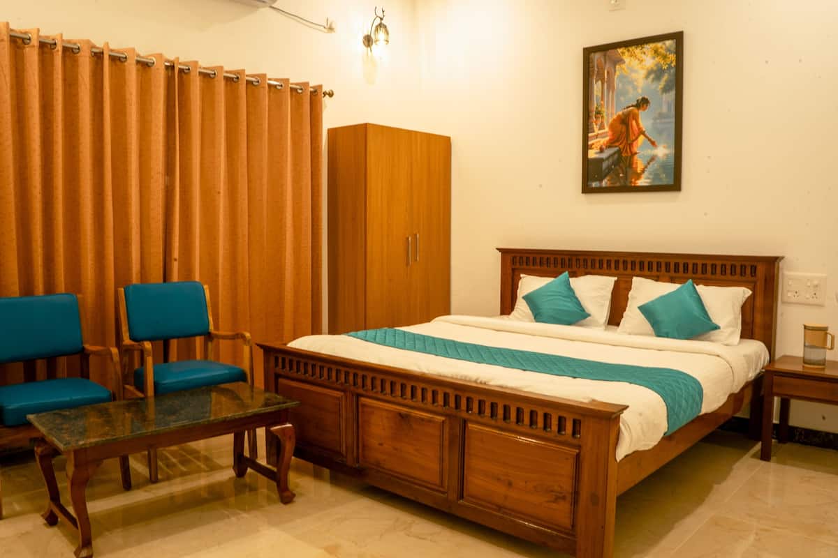 A bedroom with a wooden bed, blue chairs, a wooden wardrobe, and a painting on the wall.