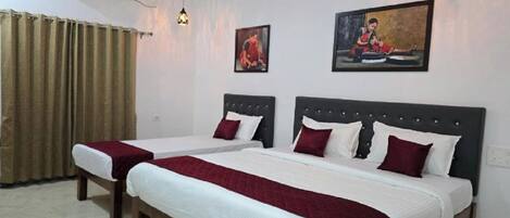 A hotel room with two beds, a large window with curtains, a wall-mounted air conditioner, and two wall-mounted pendant lights.