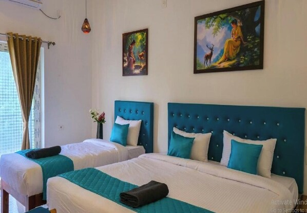 A hotel room with two beds, each with a blue headboard and white bedding. There are two paintings on the wall, one depicting a person with a deer and the other a person with a deer.