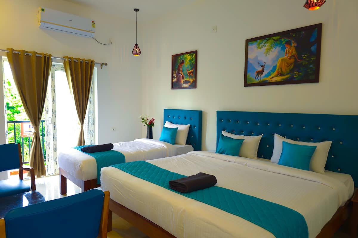 A hotel room with two beds, a desk, and a chair. There is a window with curtains, a painting on the wall, and an air conditioning unit.
