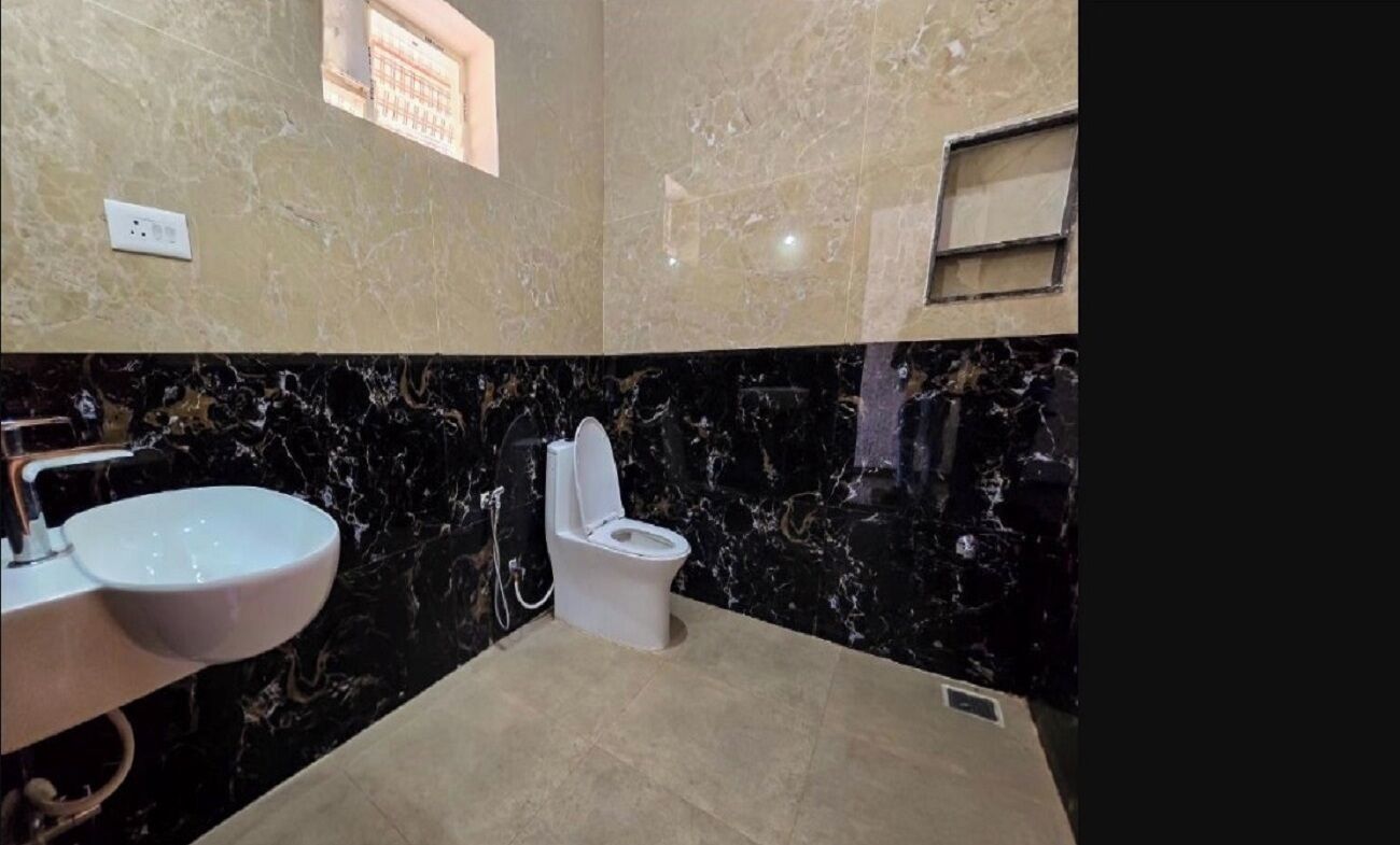 A bathroom with a marble sink, toilet, and a small window.