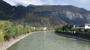 Un río con un terraplén de piedra en una orilla y un pueblo con edificios a lo largo de la ribera.
