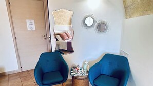 A room with a white door, a small table with two blue chairs, a woven basket, and decorative wall mirrors. - The Smile of the Sassi Rooms. Idris Superior Deluxe on Sassi view. (Matera)