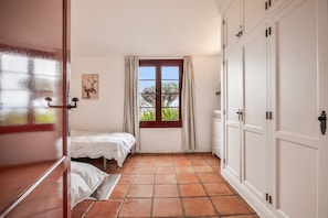Une chambre avec deux lits, une fenêtre avec des rideaux, un radiateur et une armoire.