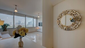A modern living room with a large window, a decorative mirror, and a vase of flowers on a white table. - Newly launched studio (Dubai)