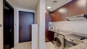 A compact kitchen with a microwave, oven, and washing machine. - Newly launched studio (Dubai)