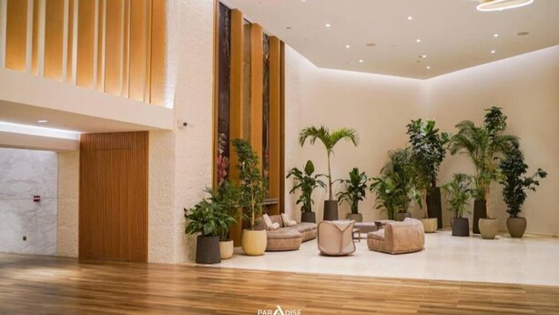 A spacious lobby with a wooden floor, a sofa, and several potted plants. - Newly launched studio (Dubai)