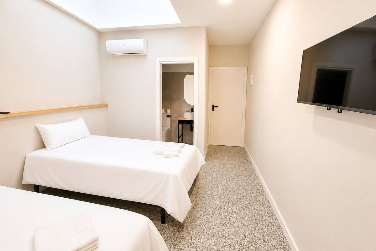 Ein Hotelzimmer mit Oberlicht, einem an der Wand montierten Fernseher und einer Tür zu einem Badezimmer.